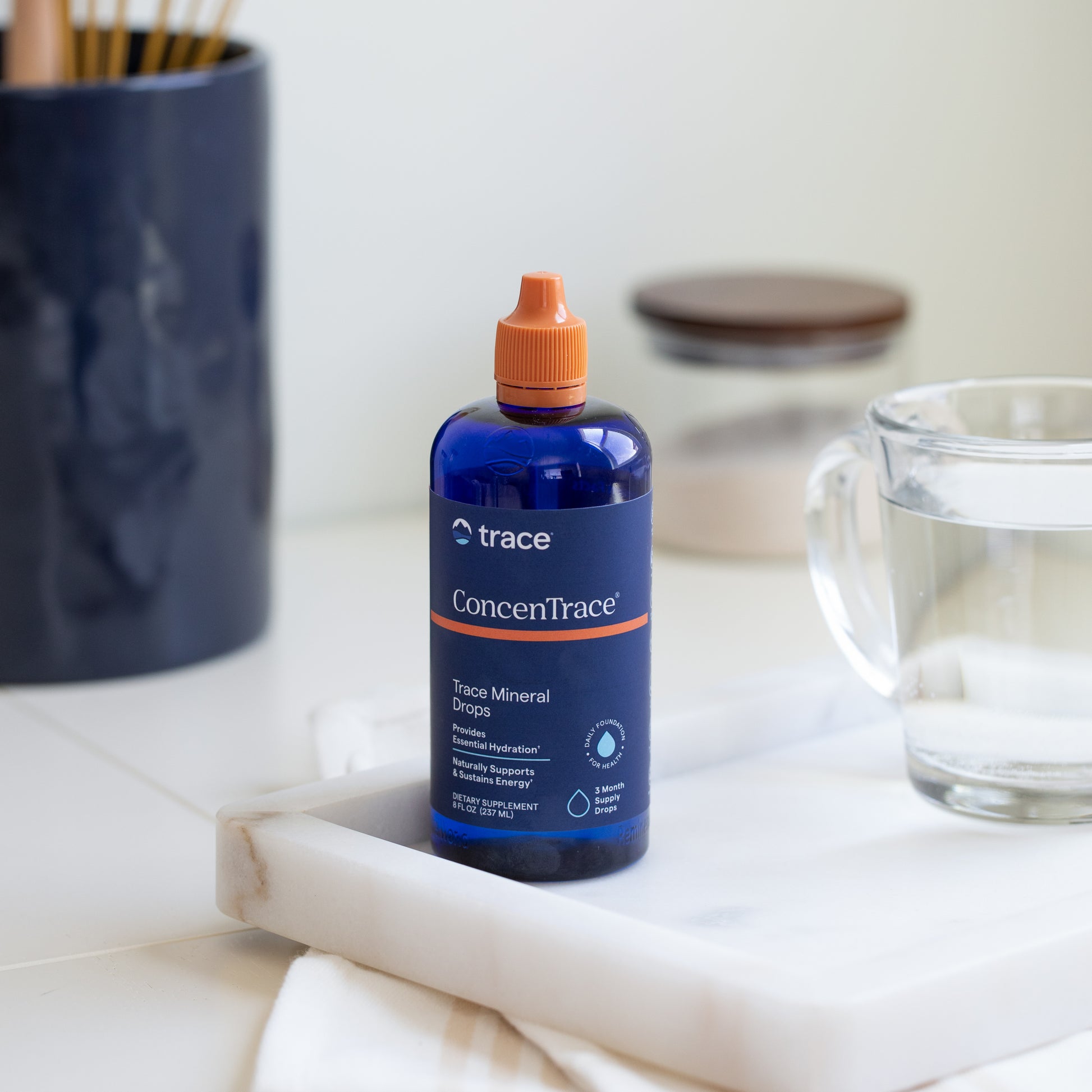 Trace minerals Concentrace joninių mineralų pakuotė 237 ml ant stalo su stikline vandens