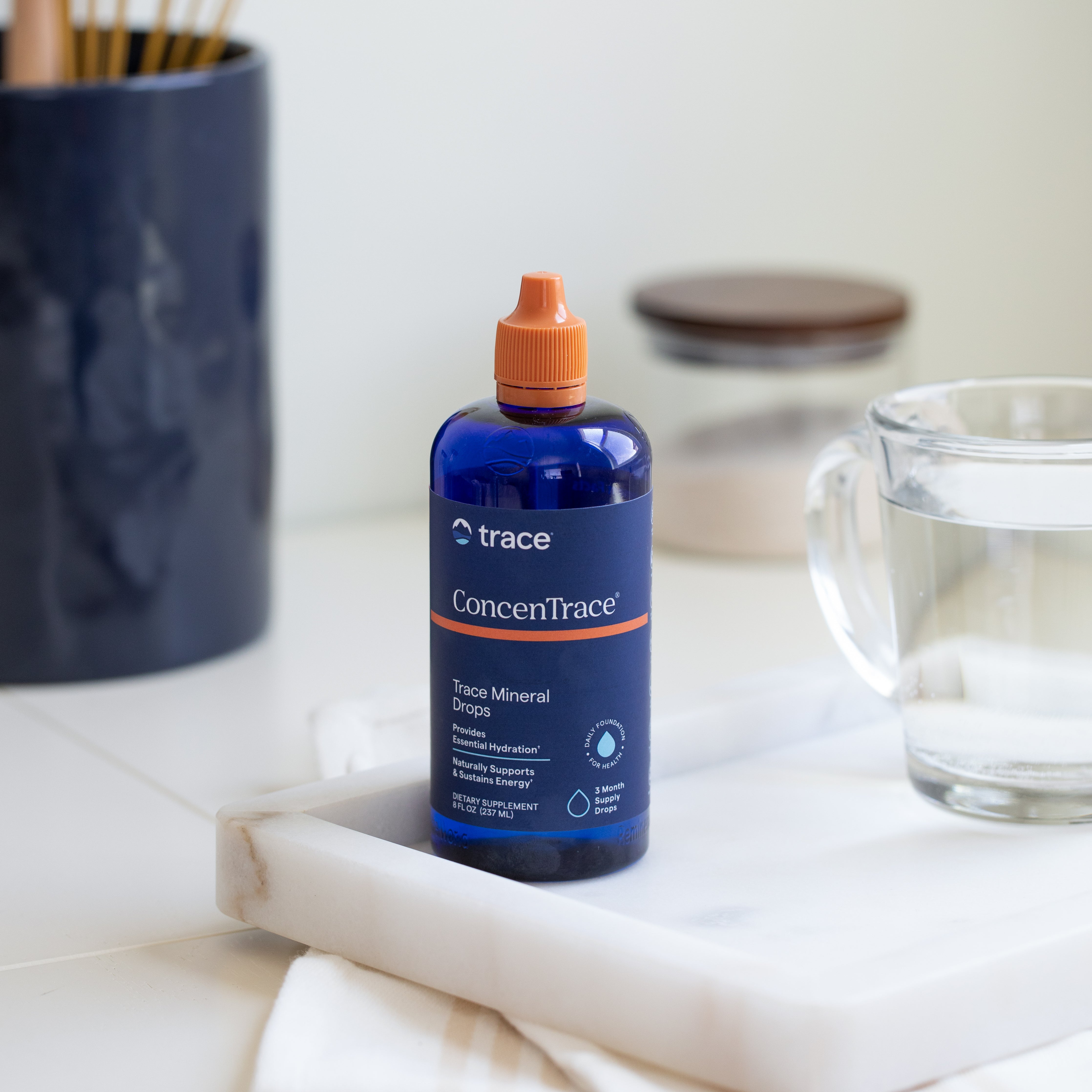 Trace minerals Concentrace joninių mineralų pakuotė 237 ml ant stalo su stikline vandens
