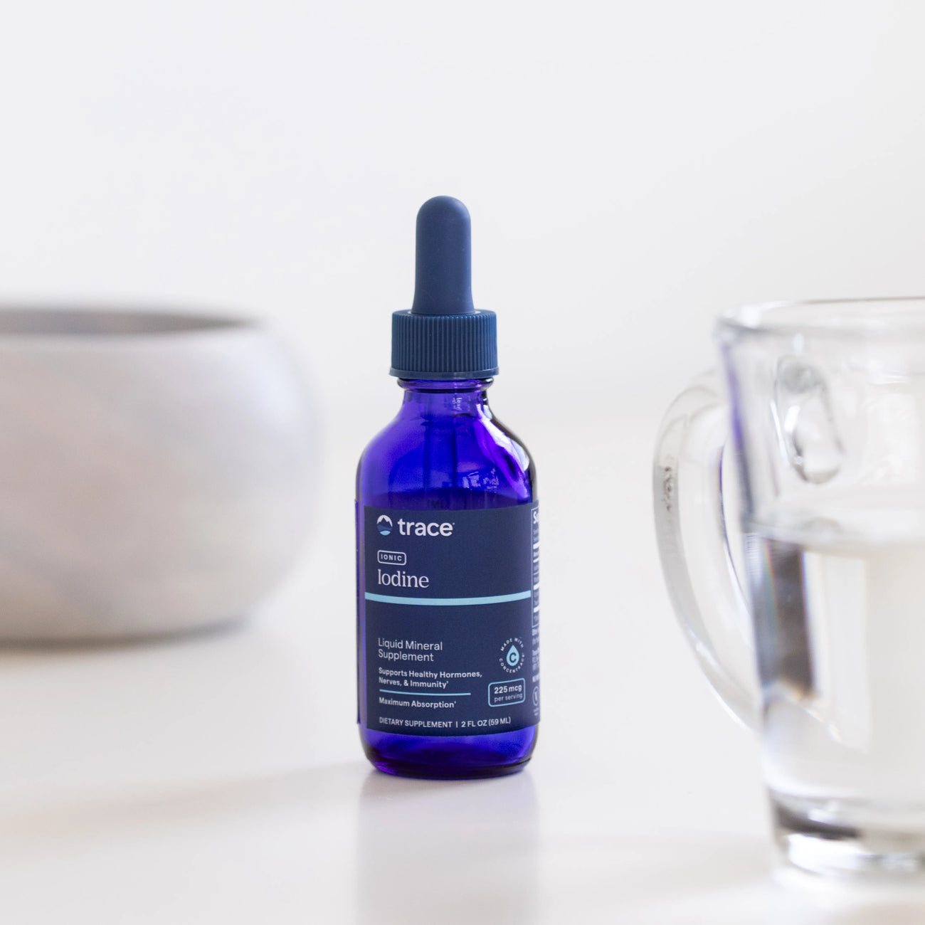 Trace Minerals joninio jodo mėlyna pakuotė. Šalia puodelis su vandeniu.
